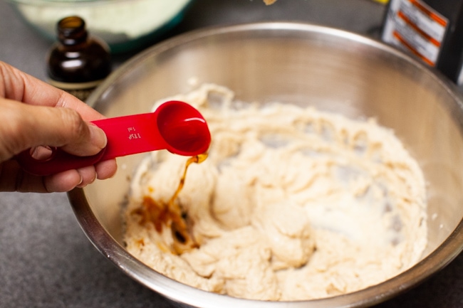 Pouring teaspoon of vanilla extract into Matcha Cookie batter from thelittlekiitchen.com