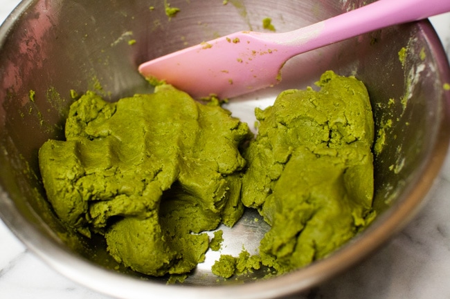 Matcha Cookie batter in metal mixing bowl with pink rubber spatula from thelittlekiitchen.com