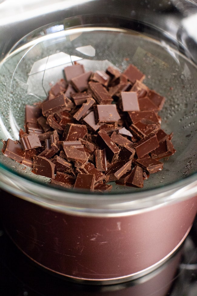Chocolate pieces melting in a glass bowl set over a pot of bowling water from thelittlekiitchen.com