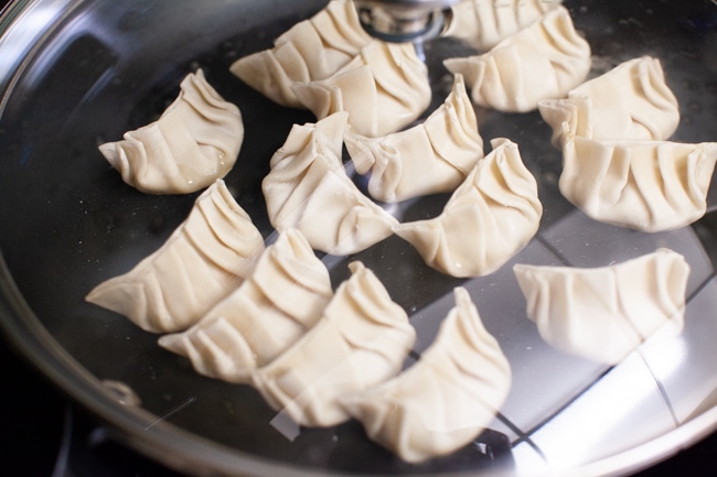 Vegetarian Dumplings cooking in a covered skillet from thelittlekiitchen.com