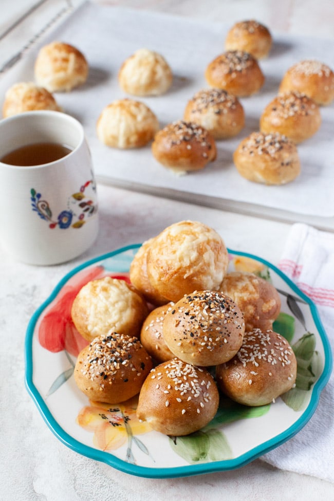 Stuffed Bagel Bites from thelittlekiitchen.com stuffed bagel bites on a floral plate with a cup of tea in the background along with more stuffed bagel bites