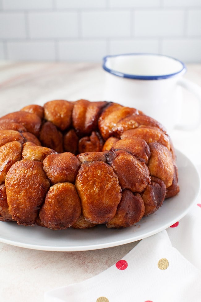 Easy Monkey Bread with Nutella from thelittlekiitchen.com monkey bread on a plate with a napkin and a pitcher with frosting in the background