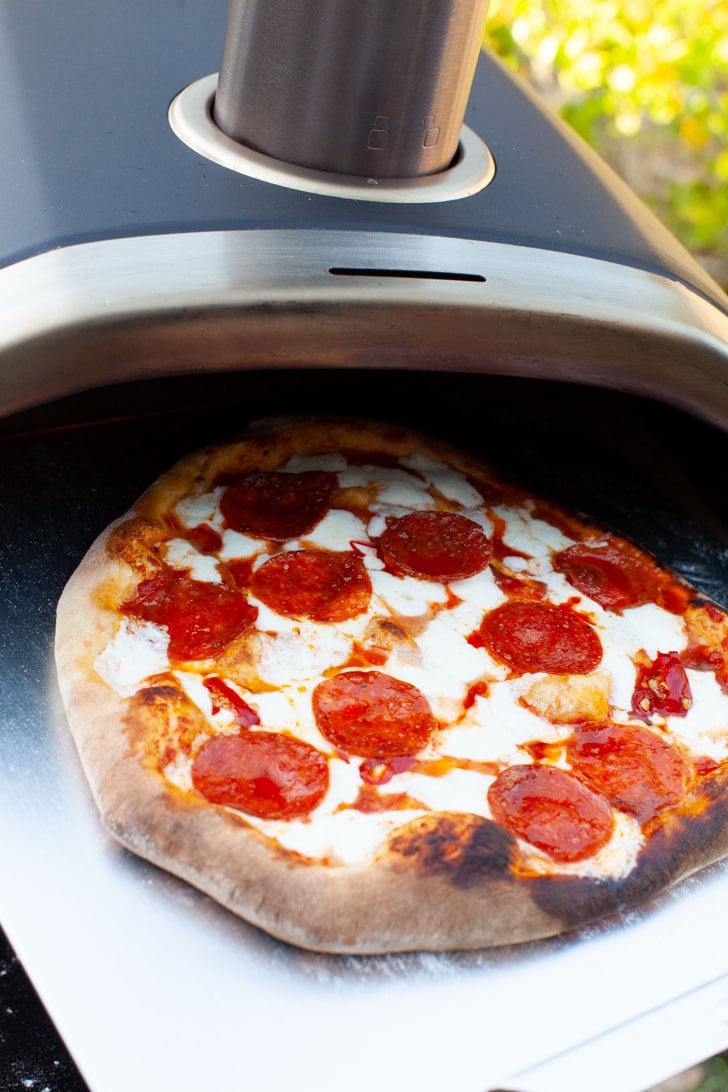 Making Pizza with Frozen Dough from thelittlekiitchen.com Pepperoni Pizza on a pizza peel coming out of a Ooni pizza oven